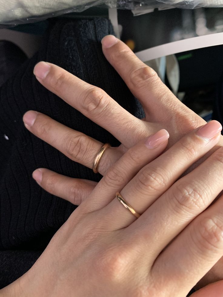 two hands holding each other with wedding rings on top of their fingers in front of them