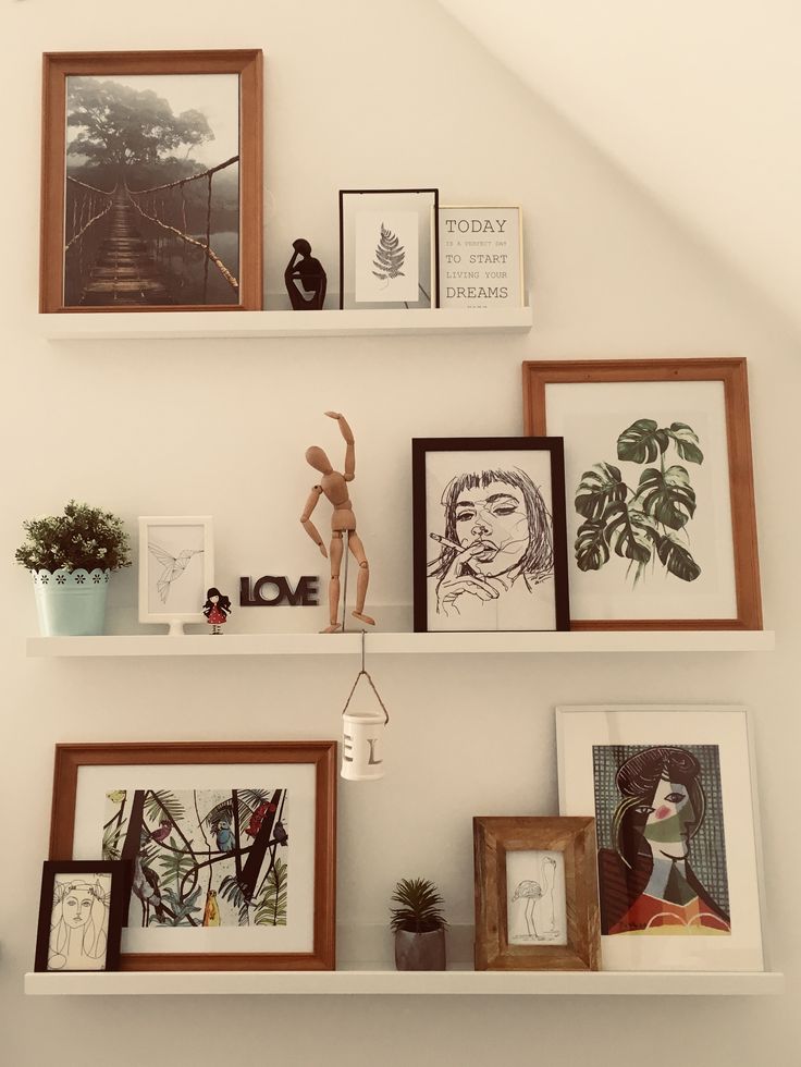 three white shelves filled with pictures and framed art