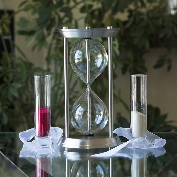 an hourglass and two candles on a glass table