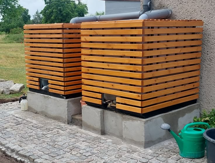 two large wooden boxes sitting next to each other on the side of a building in front of a brick wall