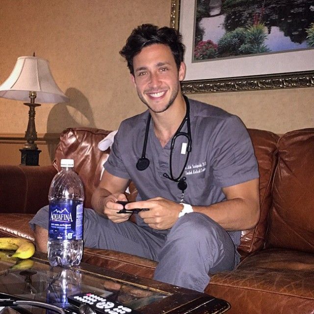 a man in scrubs sitting on a couch with a bottle of water next to him