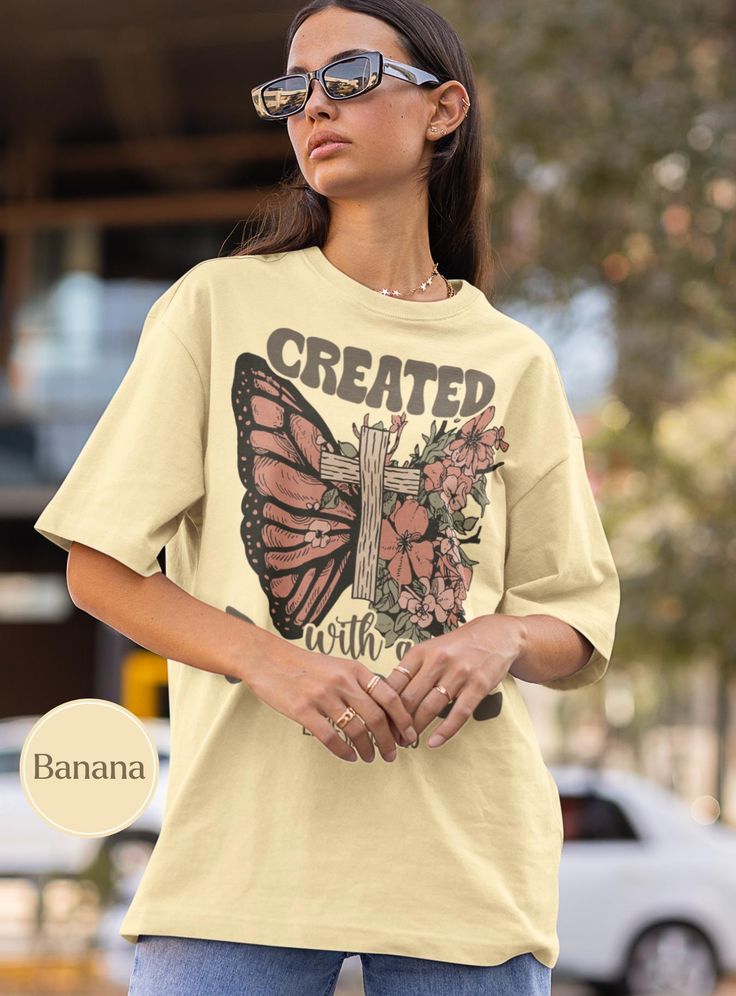 Elevate your wardrobe with our "Created with a Purpose" graphic T-shirt! Featuring a beautifully detailed design of a butterfly wing intertwined with a rustic wooden cross and blooming flowers, this shirt is not just stylish but also inspiring. The text "Created with a Purpose" and "Ephesians 2:10" serves as a meaningful reminder of strength and faith. 🦋 Perfect for casual wear or as a thoughtful gift, this T-shirt combines comfort and motivation in one unique piece. Embrace your purpose and le Created With A Purpose, Bible Verse Shirt, Inspirational Tshirts, Jesus Shirt, Jesus Shirts, A Butterfly, Bible Verse, Comfort Colors, San Jose