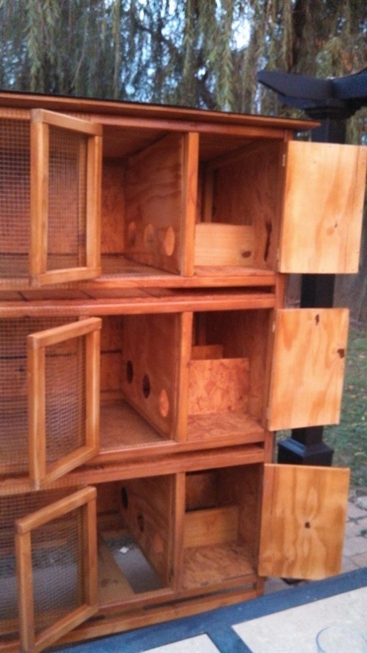 a large wooden cabinet with many compartments on the top and bottom, in front of some trees