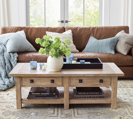 a living room with a couch, coffee table and books on top of the tables