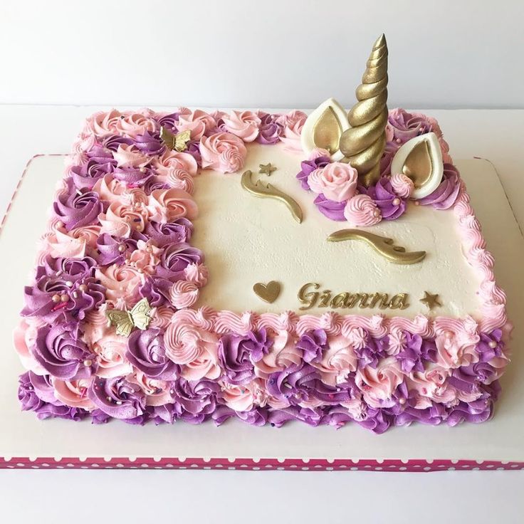 a birthday cake decorated with flowers and a unicorn horn on it's top is sitting on a table