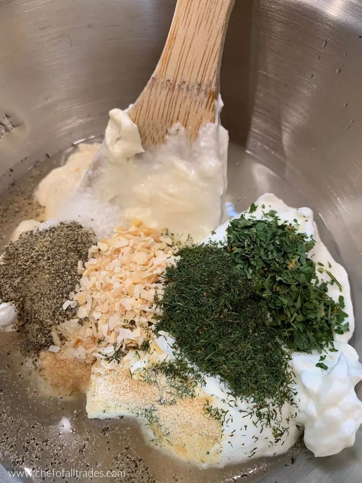 the ingredients are being mixed together in a silver bowl with a wooden utensil