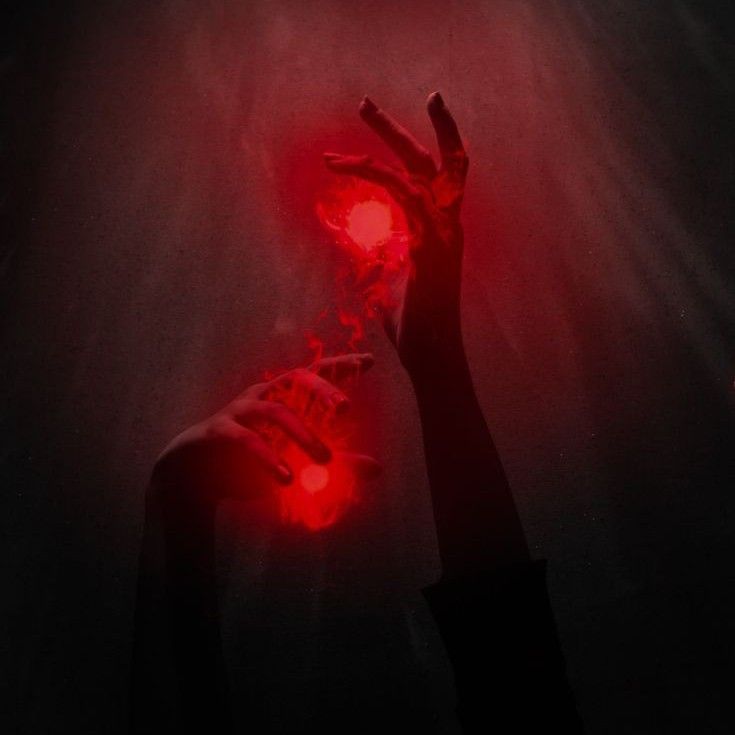 a person holding their hands up in the air with red light coming from behind them