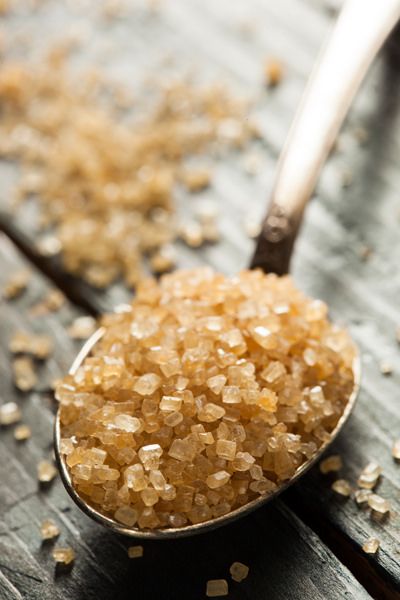 a spoon filled with sugar sitting on top of a wooden table