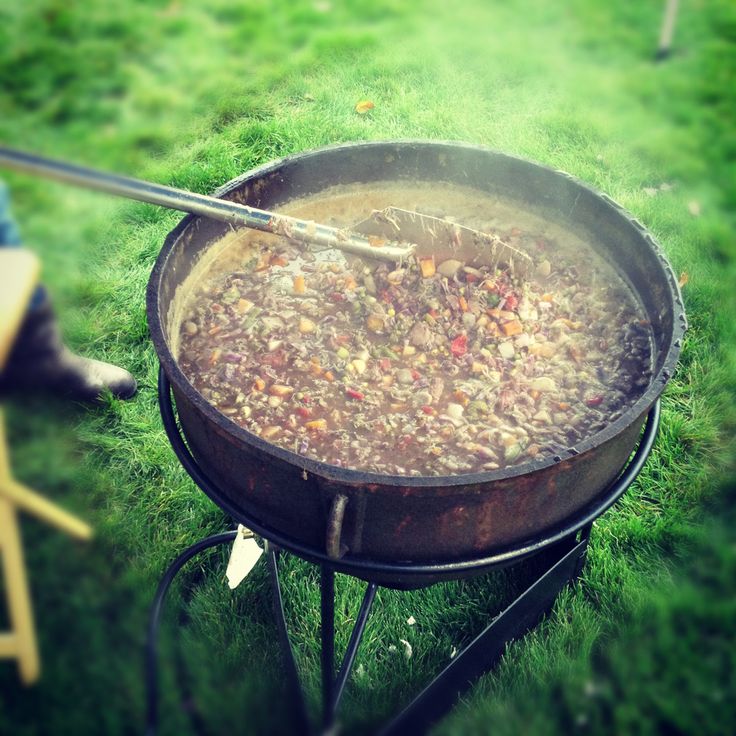 a large pot filled with lots of food on top of a grass covered field