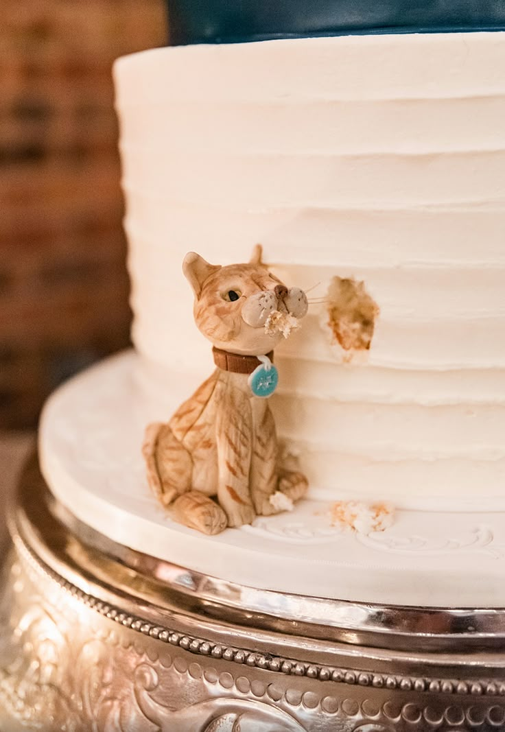 a cat figurine sitting on top of a white cake