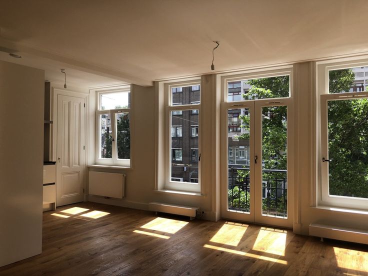 an empty room with three windows and wooden floors