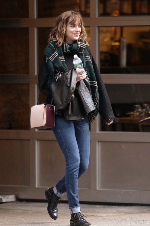 a woman is walking down the street with her hand in her pocket and holding a purse