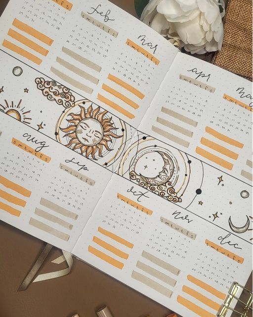 two calendars with sun and moon designs on them next to some pens, scissors and flowers