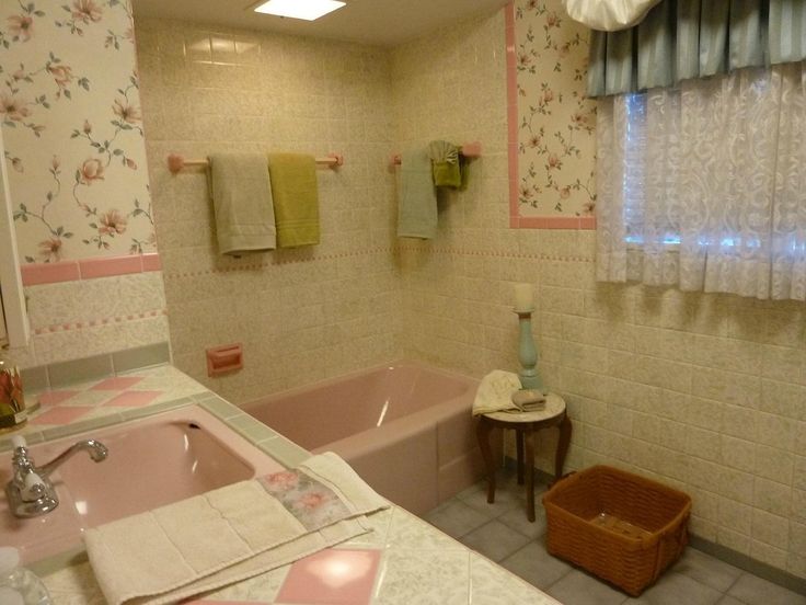 a pink bath tub sitting next to a white sink under a window in a bathroom