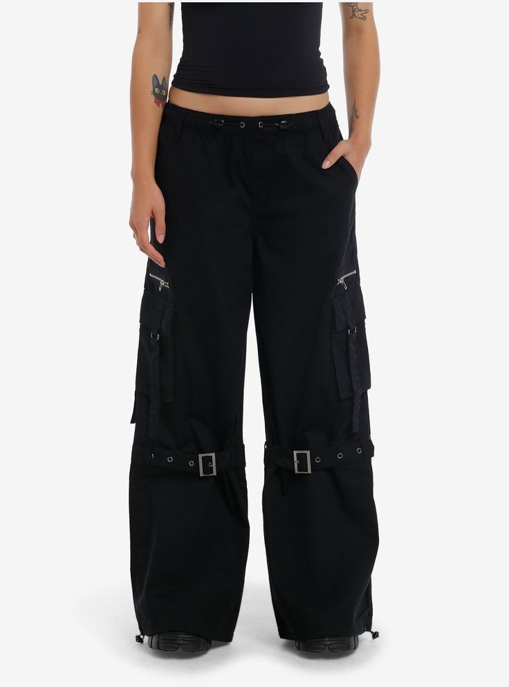 Your street style has never been edgier! These low rise  black pants have a wide leg fit and feature grommet strap detailing around the shin. Comes with cargo pockets with zipper detailing up top  plus hip and back pockets. Complete with an elasticated waist with bungee cord detailing on the waist and ankles.100% cottonWash cold; dry lowNon-stretch materialRise: 12''Inseam: 30''ImportedListed in junior sizesModel is 5'8''Model wears size Medium Black Alternative Pants With Zipper Closure, Alternative Black Pants With Zipper Closure, Alternative Style Black Pants With Zipper Closure, Black Alternative Style Pants With Zipper Closure, Edgy Straight Leg Cargo Pants With Pockets, Edgy Straight Leg Cargo Pants, Edgy Wide Leg Cargo Jeans With Multiple Pockets, Black Wide Leg Pants For Concert, Edgy Black Parachute Pants