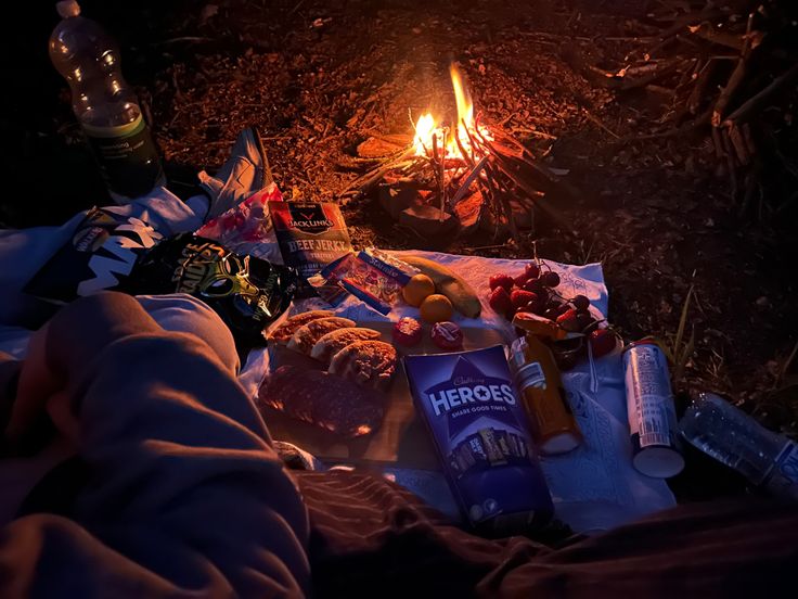 a campfire with food and drinks on the ground