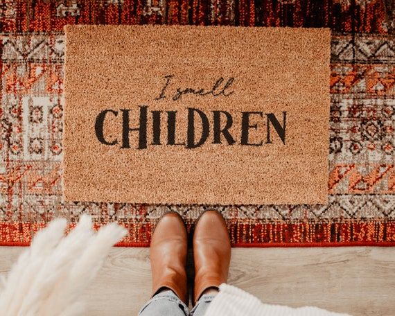 a person standing in front of a door mat that says nice package