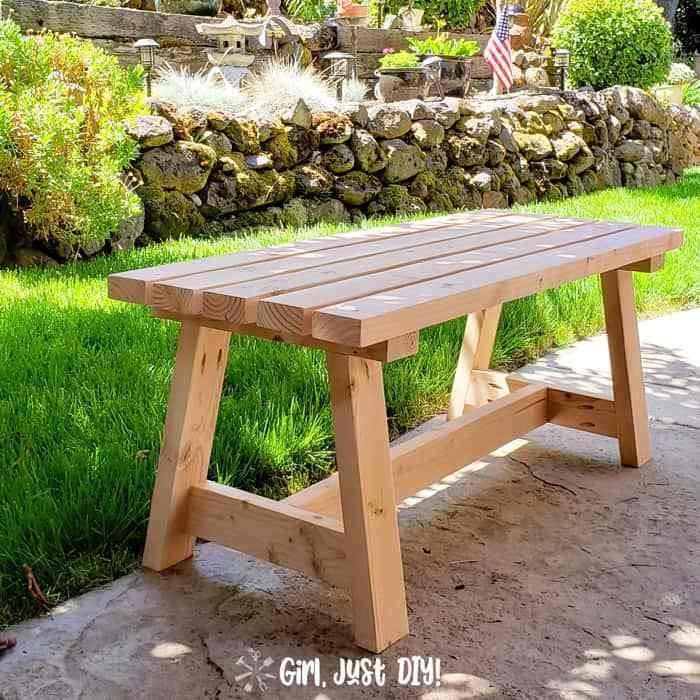 a wooden bench sitting on top of a lush green field next to a stone wall