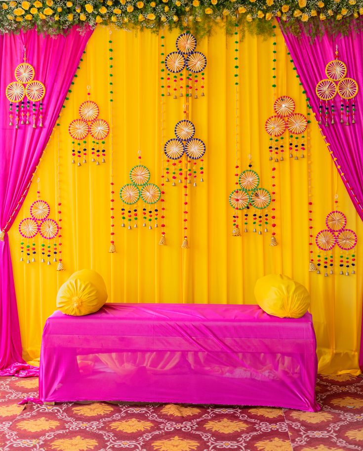 a decorated stage with yellow and pink drapes, flowers and decorations on the wall