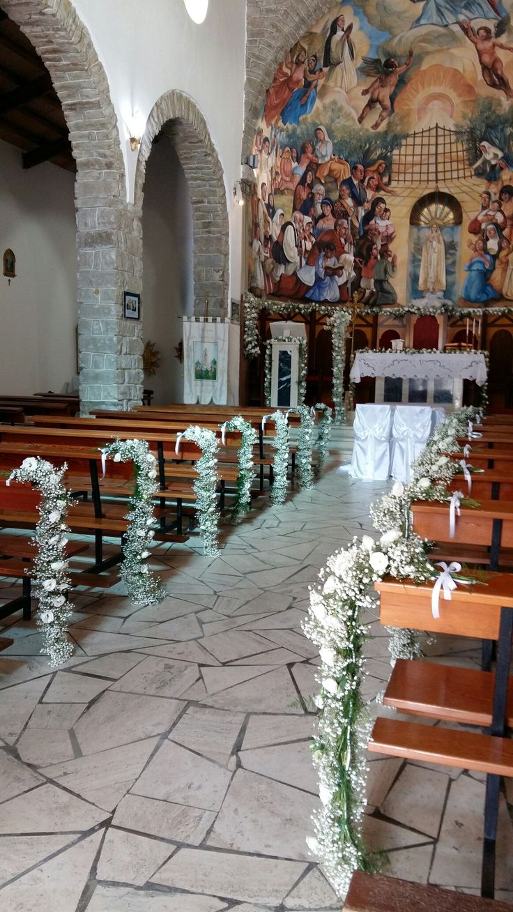 the inside of a church with wooden benches and floral garlands on the pews