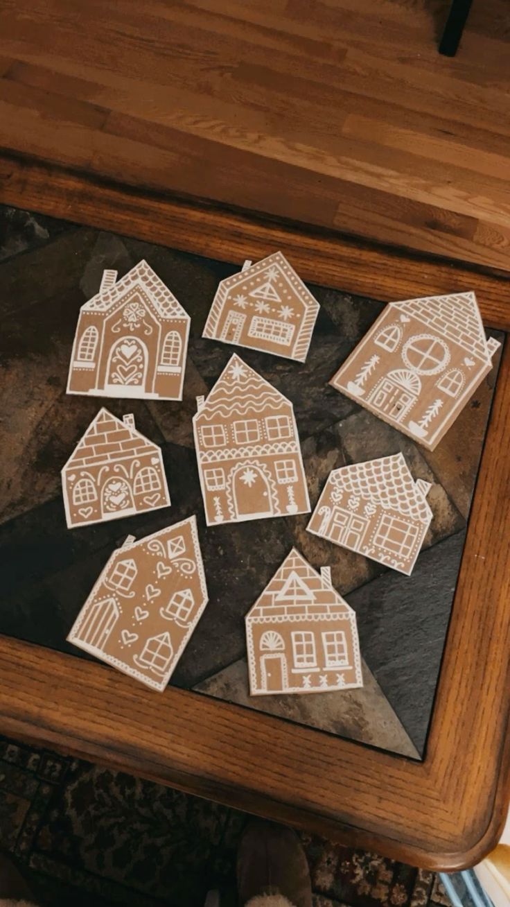 wooden cutout houses sitting on top of a table next to a person's feet