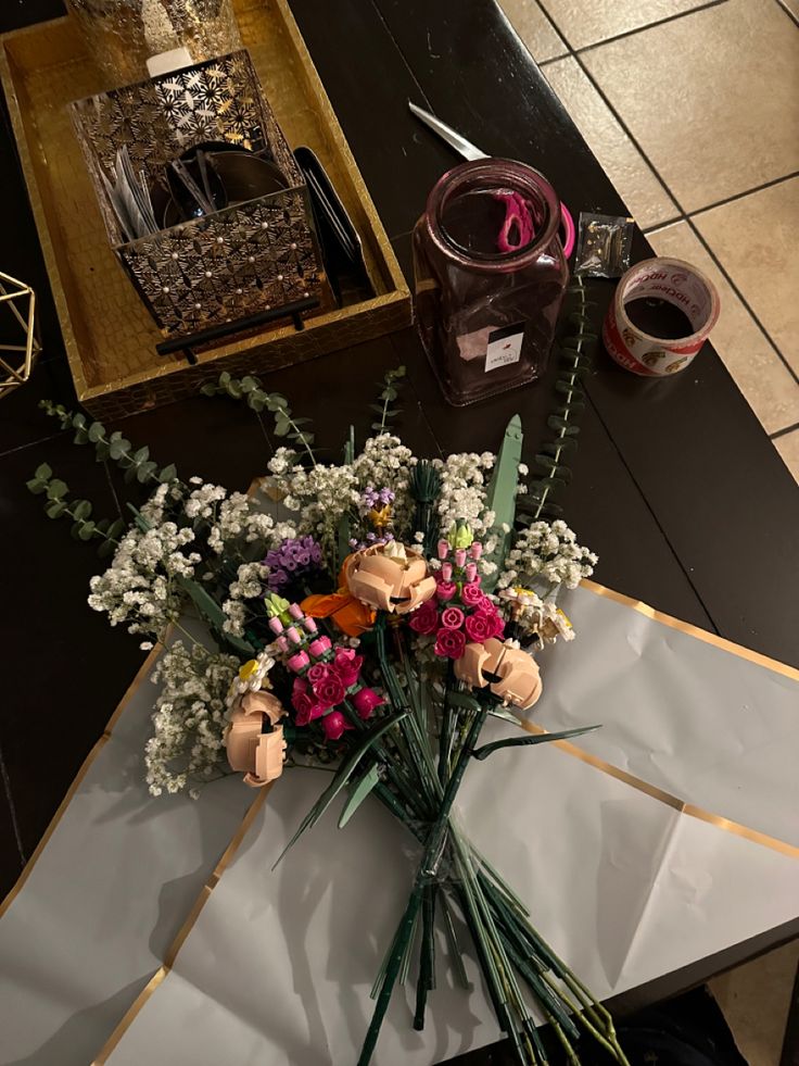 a bunch of flowers sitting on top of a table next to a box and scissors