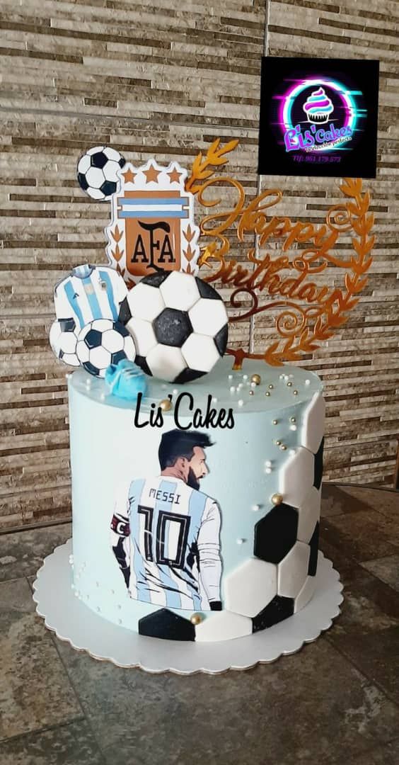 a soccer themed cake is on display in front of a brick wall with an ad