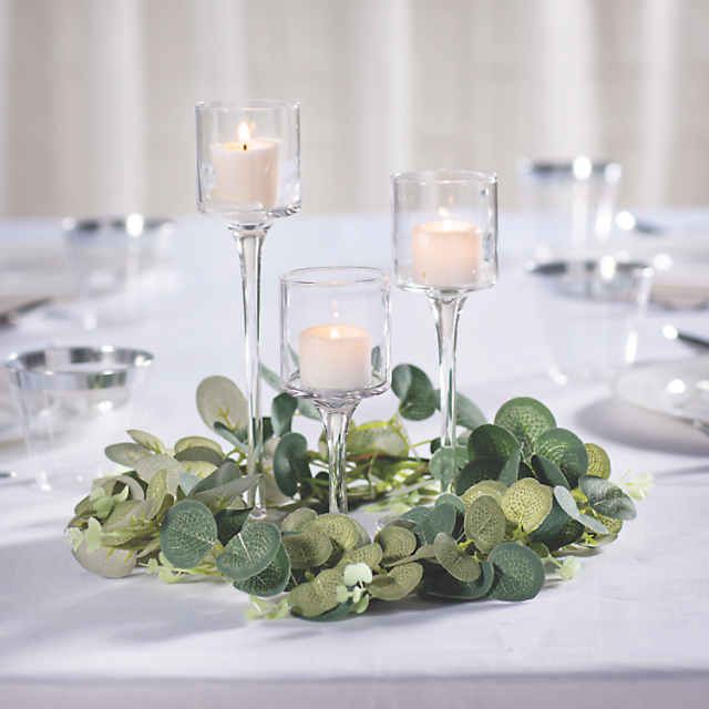 candles are lit on the table with greenery