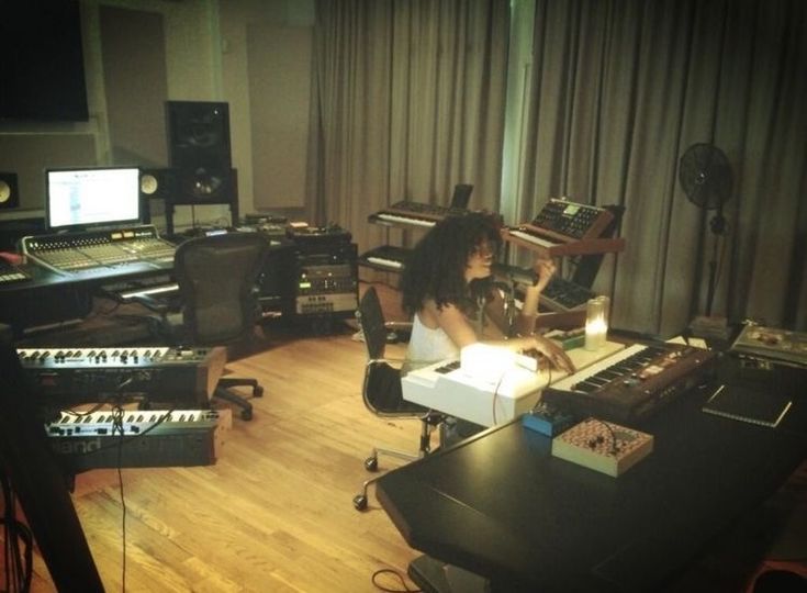 a woman sitting at a desk in front of a sound board and mixing equipment on the floor