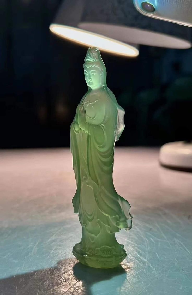 a green statue sitting on top of a table under a light