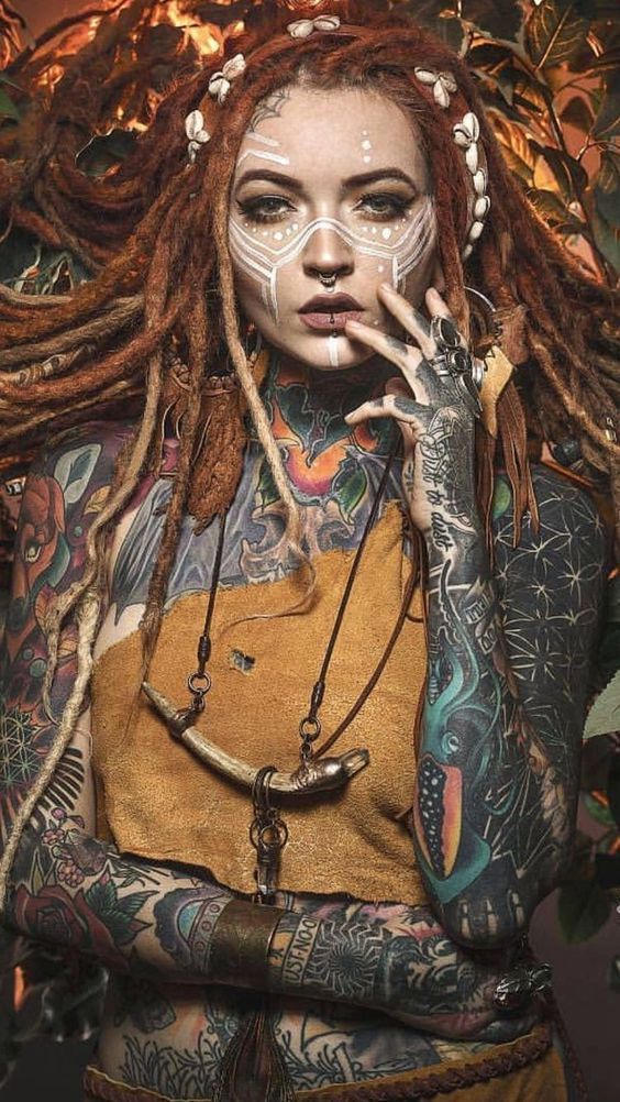 a woman with dreadlocks and tattoos on her face is posing for the camera