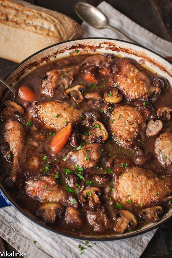 a bowl filled with meat and mushrooms next to bread