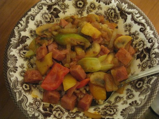 a bowl filled with meat and vegetables on top of a wooden table next to a spoon