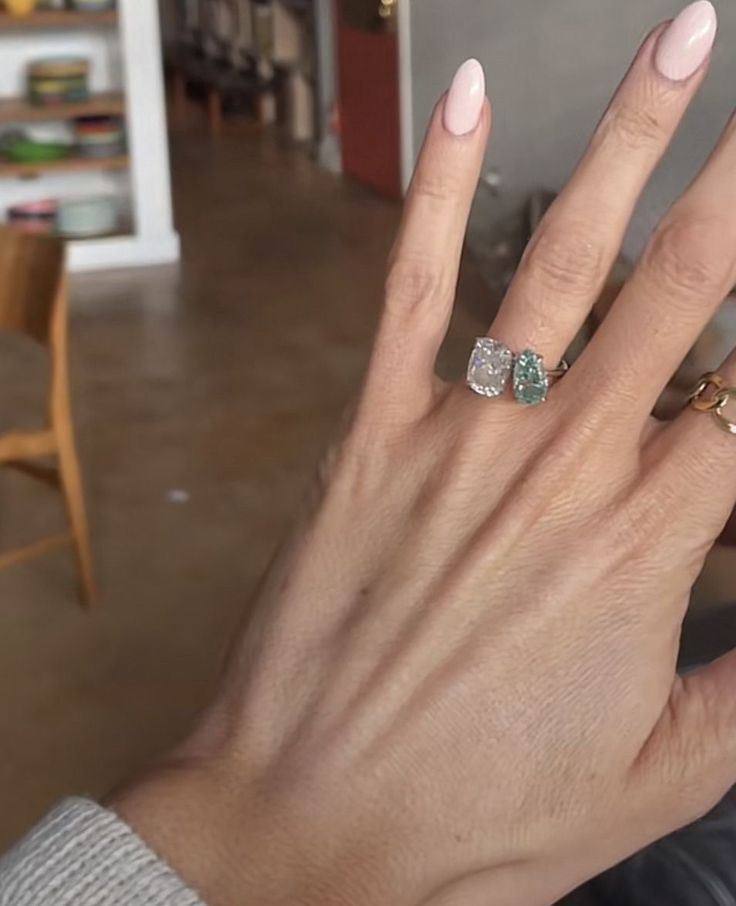 a woman's hand with two different rings on her fingers, and one is holding the other