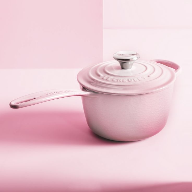 a white pot with a lid on a pink surface