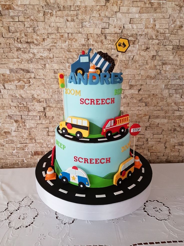 a three tiered cake is decorated with cars and trucks on the top, along with street signs