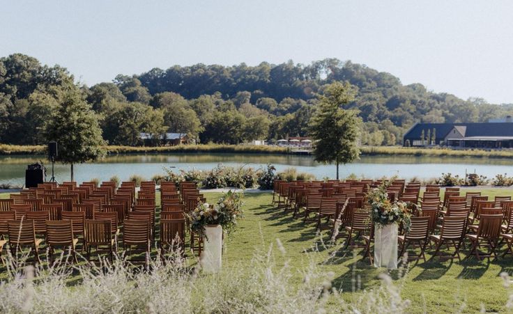 rows of wooden chairs set up in front of a lake for an outdoor wedding ceremony