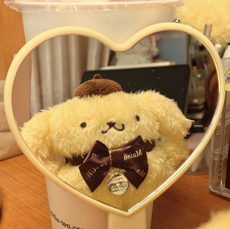 a teddy bear in a heart shaped container with a bow tie on it's head