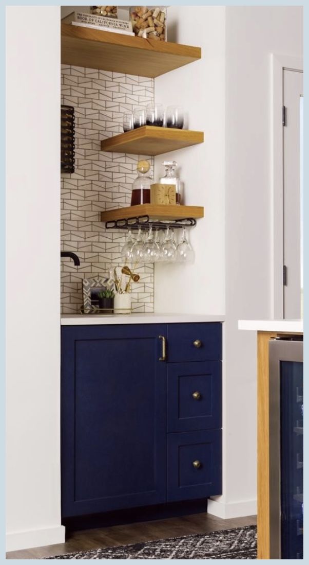 there is a wine cooler in the corner of this kitchen with blue cabinets and shelving