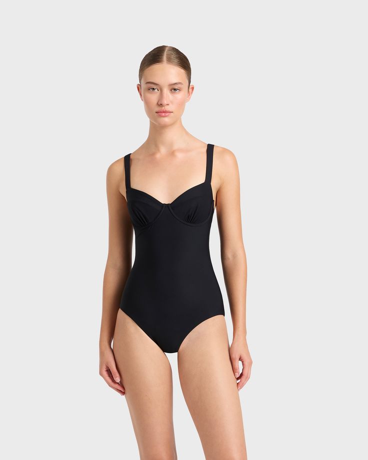 A modern classic, the Loures balconette one piece in black is cut from our luxury, Italian Sculpteur® fabric with patented 3-D stretch technology that flatters the silhouette. Loures features comfortable, wide, adjustable shoulder straps, an underwire for bust support and flattering gathers at mid bust. Ideal for those seeking tummy control, Loures is a classic swimsuit that will endure for years to come. Best suited to bust sizes B, C & D.Luxury fabric sustainably made in Italy. Elegant Black Seamless Swimwear, Black Fitted Swimwear With Wide Straps, Elegant Compressive Full Coverage Swimwear, Elegant Sculpting Swimwear In Nylon, Elegant Sculpting Nylon Swimwear, Elegant Sculpting Full Coverage Swimwear, Black Nylon Swimwear With Padded Cups, Elegant Black Swimwear With Built-in Bra, Elegant Compressive Solid Swimwear