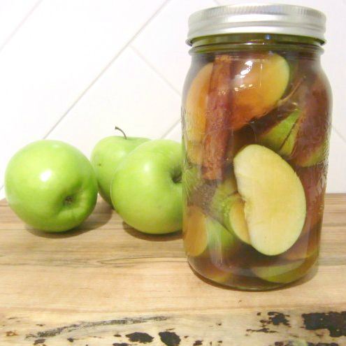 an apple is in a jar next to two green apples