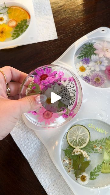 a person is holding a glass with flowers and water in it on a tray next to other dishes