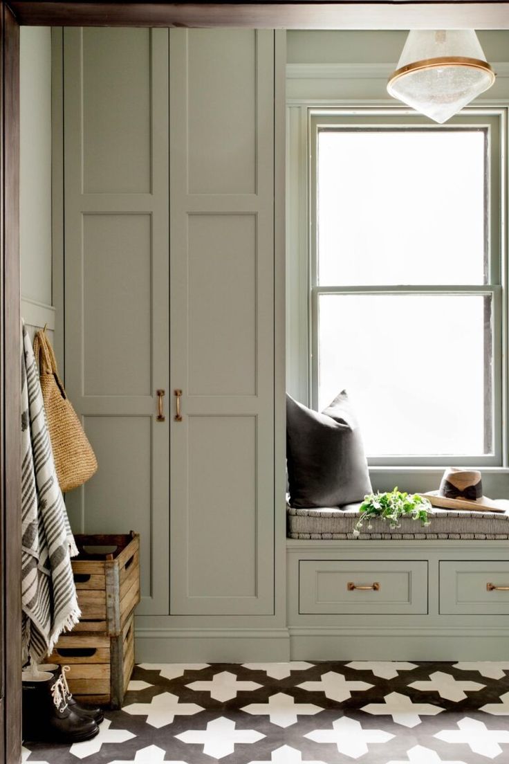 a window seat in the corner of a room next to a cabinet and coat rack