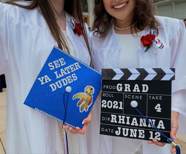 two girls in graduation gowns hold up their diplomas