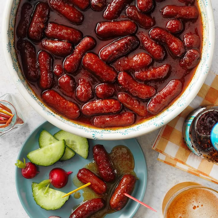 a bowl filled with lots of hot dogs next to cucumbers and pickles