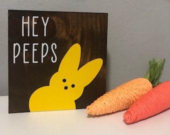 two carrots sitting next to a sign that says hey peeps on the side