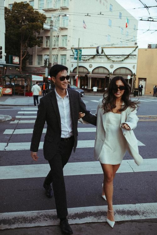 a man and woman walking across a cross walk