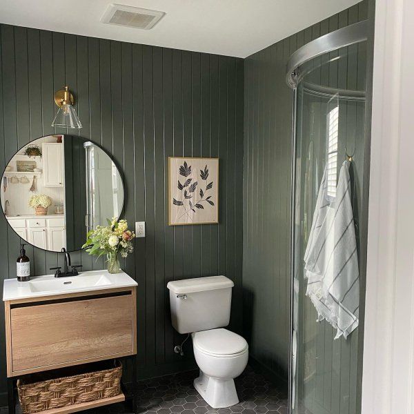 a white toilet sitting next to a walk in shower under a bathroom mirror above a sink