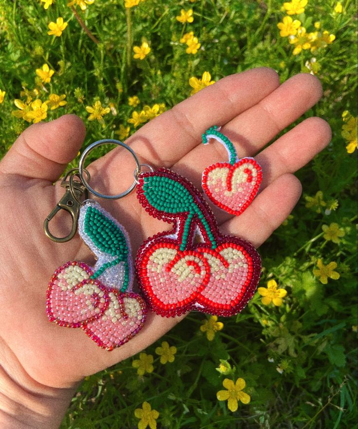 someone is holding three keychains in their hand, each with different designs on them