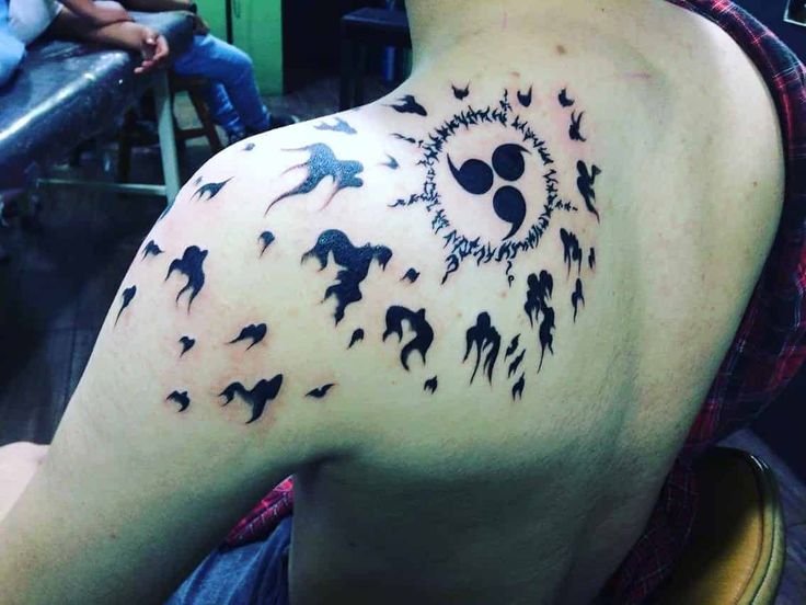 the back of a man's shoulder with birds and sun tattoo design on it